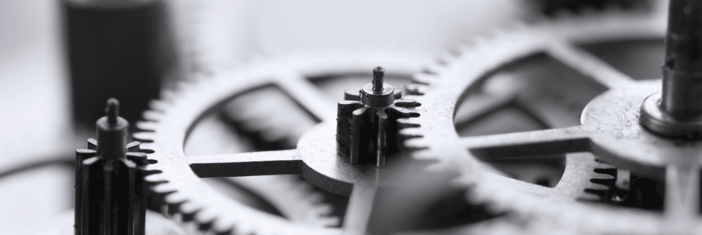 Closely cropped in image of three gears. The largest gear is on the far right, the medium gear is in the center, and the small gear is in the far left corner mostly cropped out of the image. 